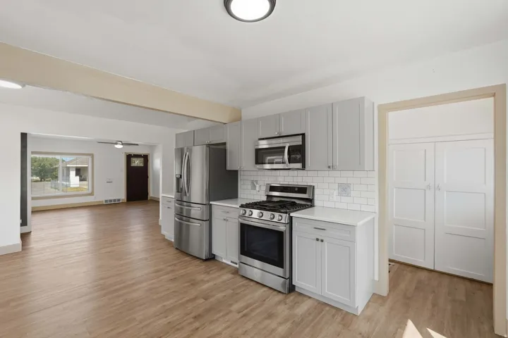 Kitchen featuring stainless steel appliances, light gray cabinetry, white subway tile backsplash, and light wood-finish flooring
