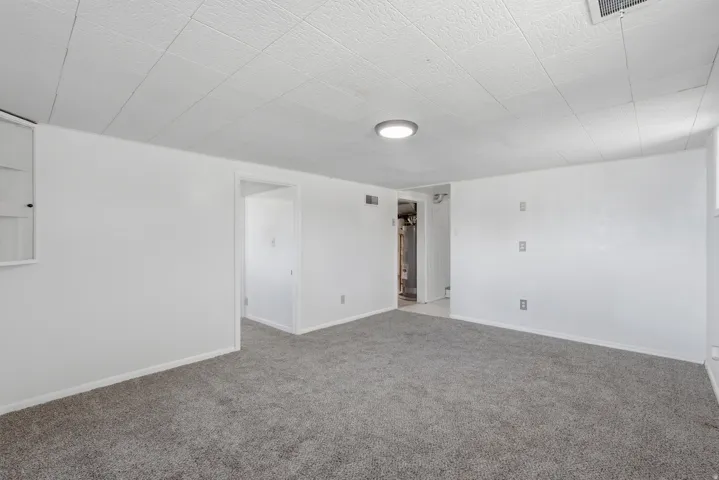 Carpeted interior space with white painted walls, white trim, and a drop ceiling