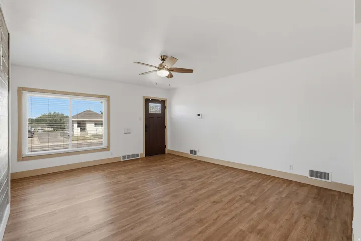 Spacious interior with wood-finish flooring, white walls, and a ceiling fan