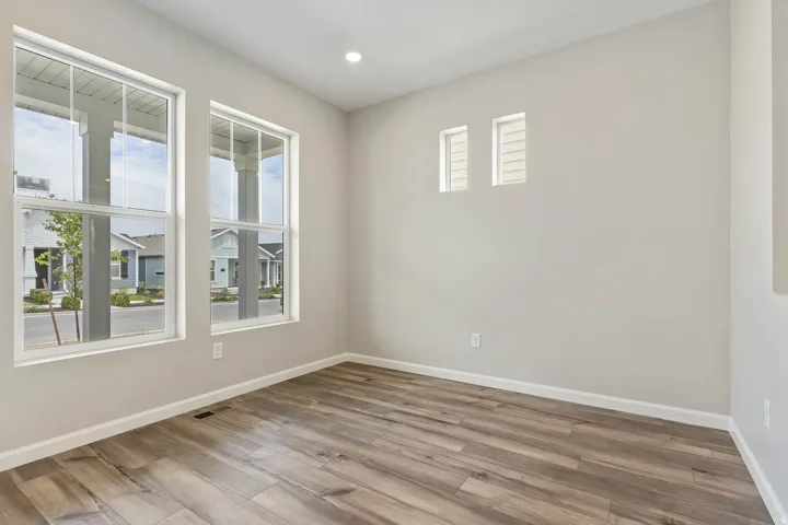 Spacious room featuring two large windows and two smaller transom windows, wood-finish flooring, recessed lighting, and neutral wall tones
