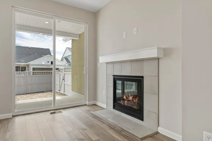 Wood-finish flooring throughout, featuring a tiled fireplace with a white mantel and hearth