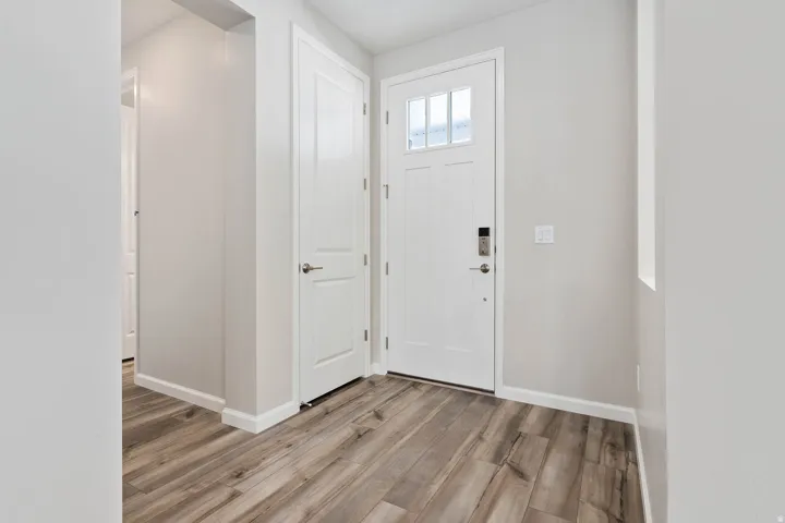 Entryway featuring wood-finish flooring, a white paneled door with frosted glass inserts, and a smart lock system