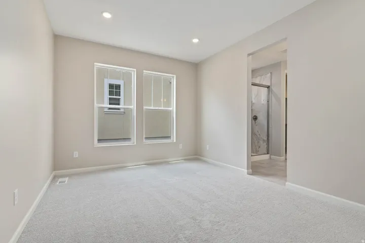 Spacious room featuring light-colored carpeting, recessed lighting, and two bright windows