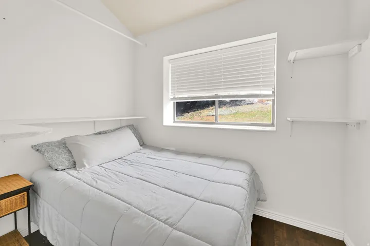 Bright room featuring dark wood-finish flooring and a window with blinds