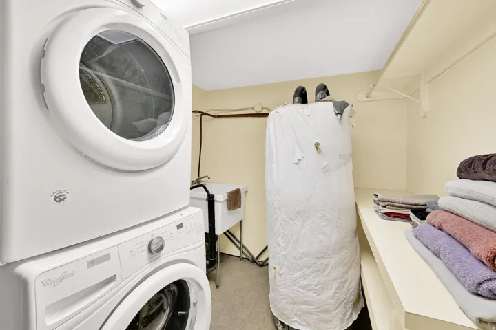 Dedicated laundry area featuring a stacked washer and dryer, utility sink, and built-in shelving for organization
