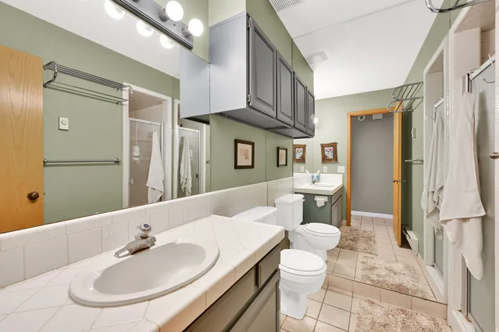 Bathroom featuring an extended vanity with tile countertop, integrated sink, and full-wall mirror