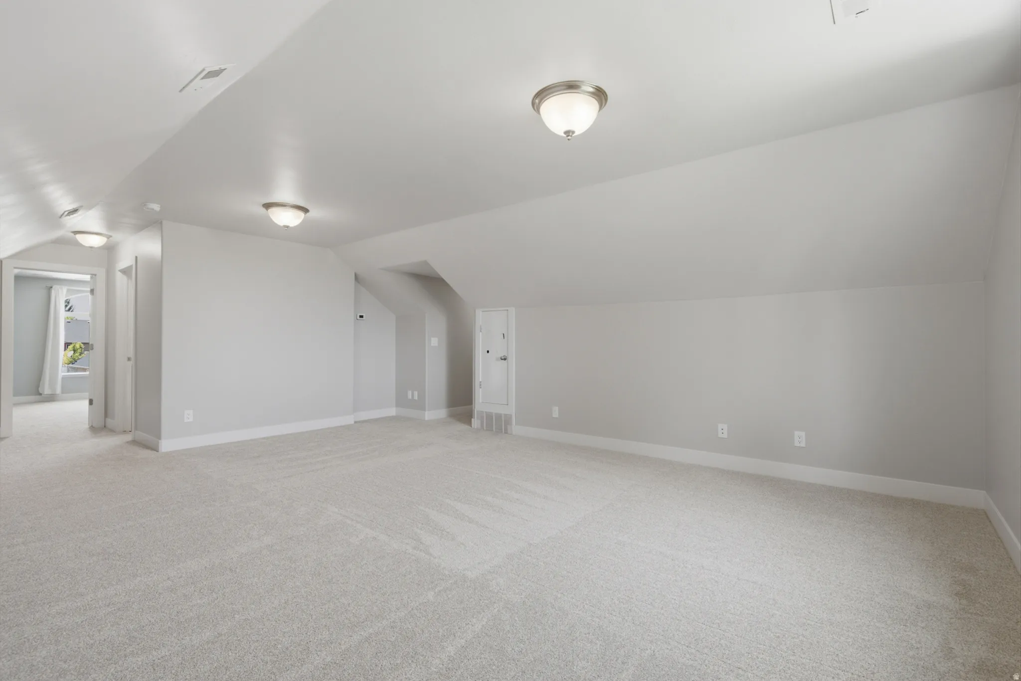Expansive carpeted room featuring vaulted ceilings, neutral wall tones, and recessed lighting