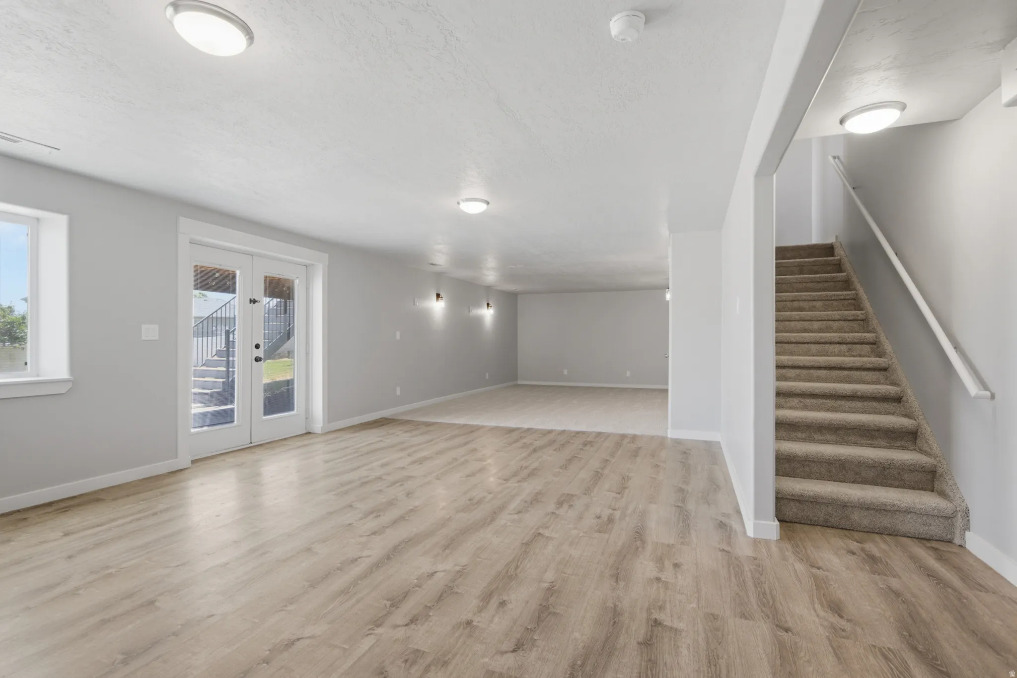 Spacious room featuring wood-finish flooring, light grey walls, and recessed lighting