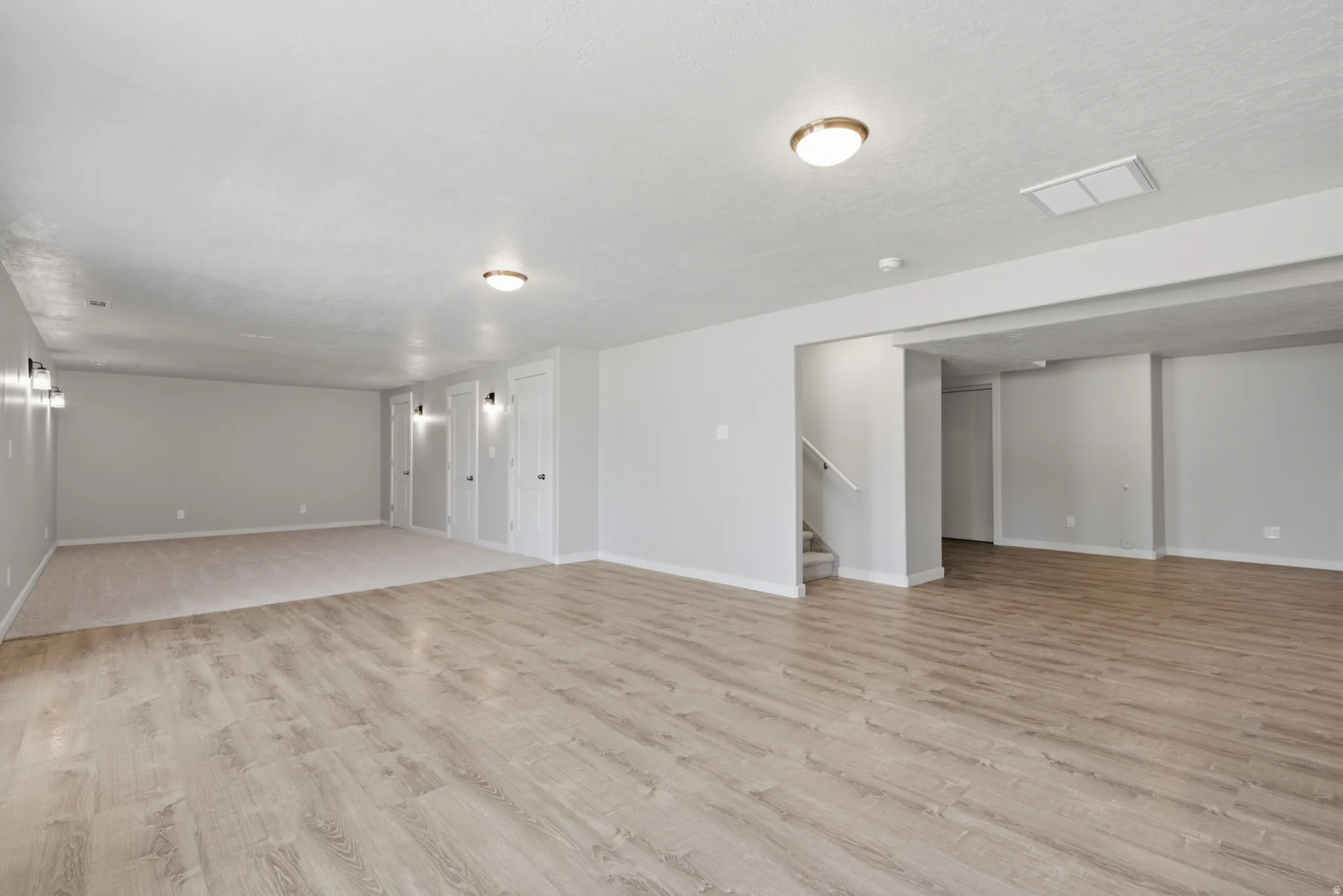 Spacious room featuring light wood-finish flooring, neutral gray walls, and recessed lighting