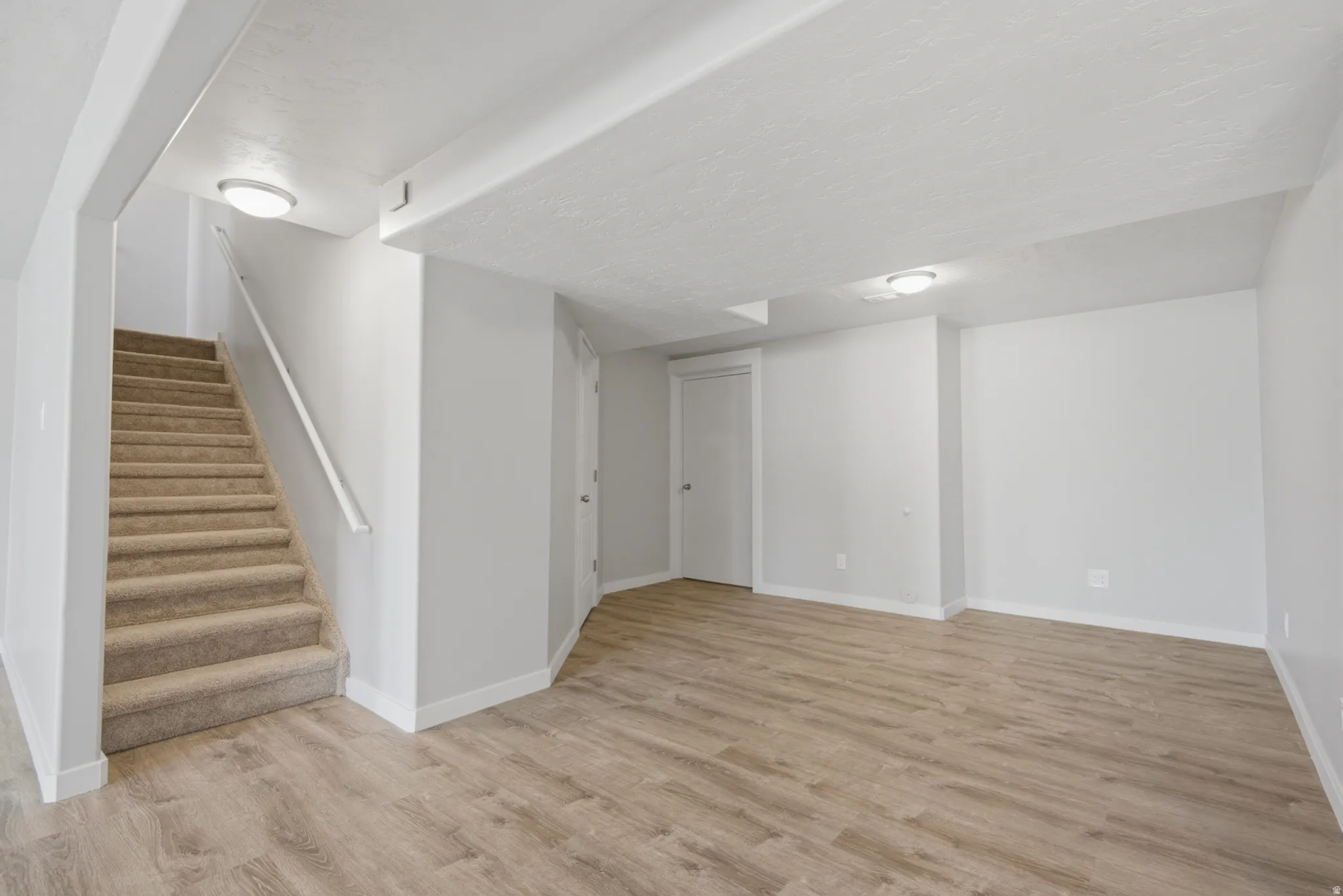 Spacious room featuring wood-finish flooring, light grey painted walls, white trim, and flush-mount ceiling lighting