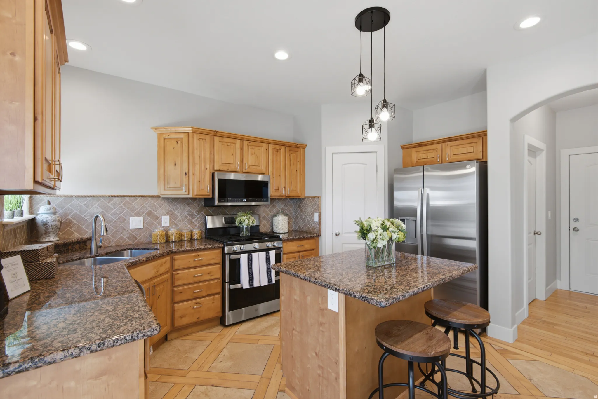 Kitchen featuring a central island with countertop seating, stainless steel appliances, wood cabinetry, recessed lighting, and a tile backsplash