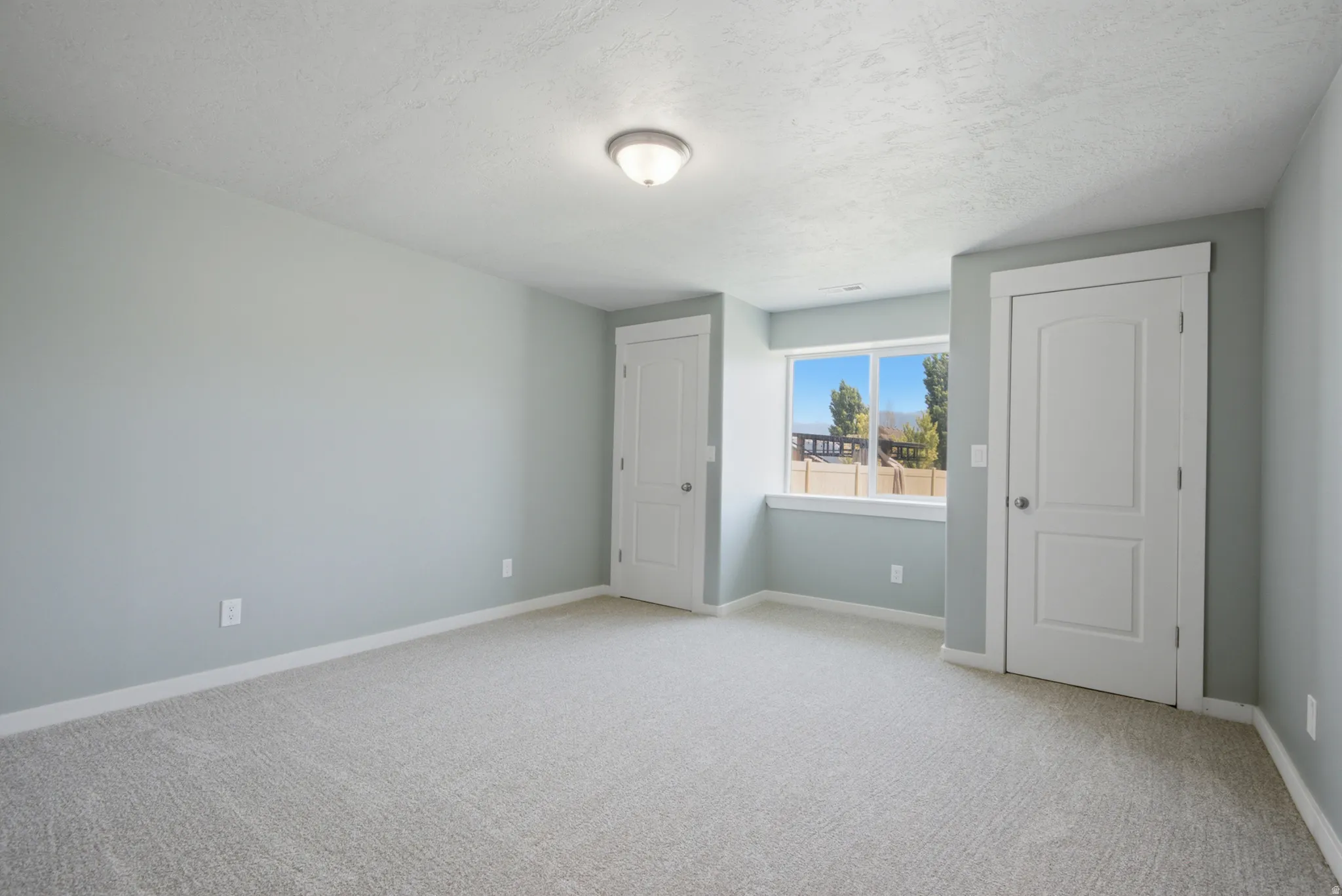 Spacious room featuring light gray carpeting and cool-toned wall paint
