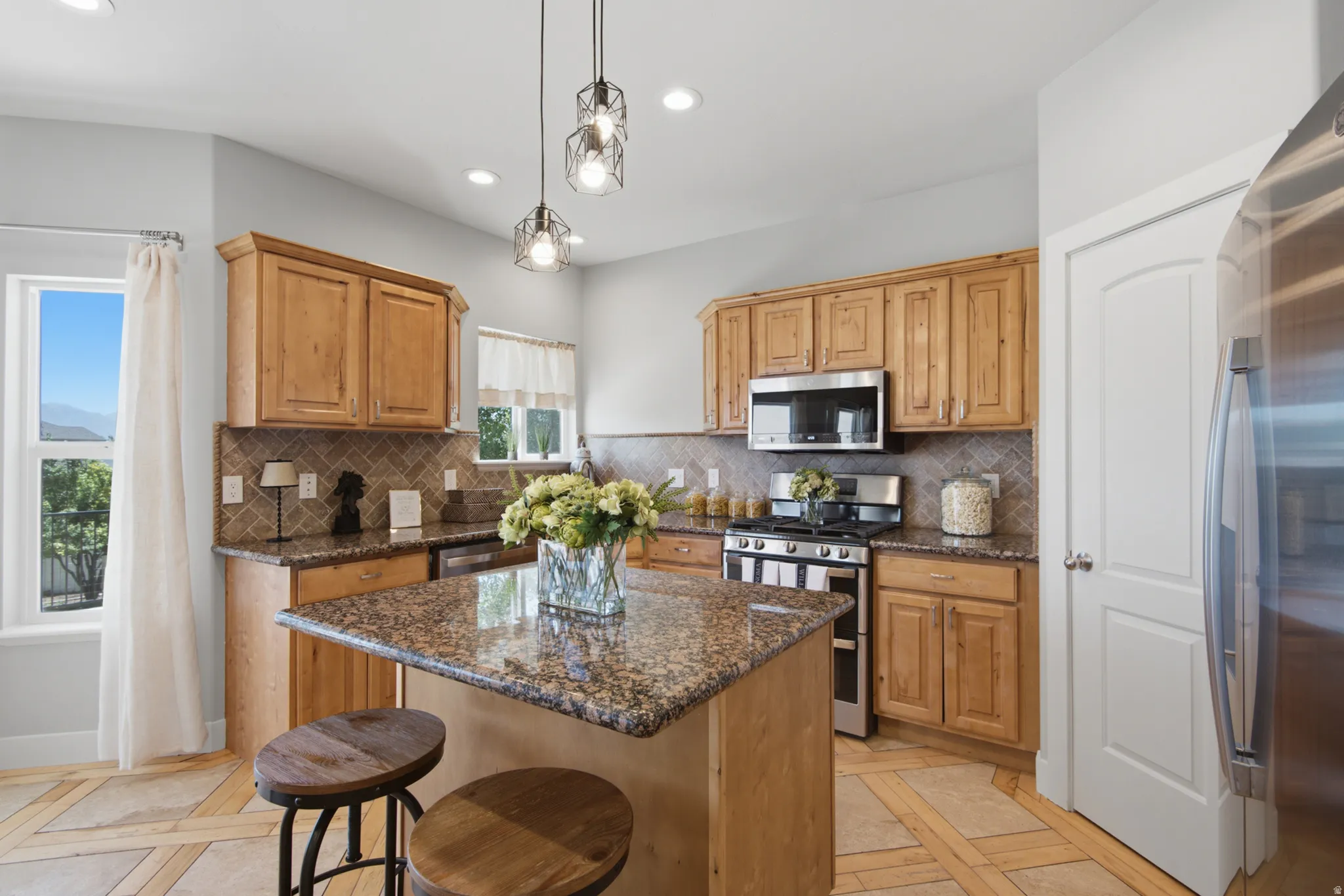 Kitchen featuring light wood cabinetry, granite countertops, a tiled backsplash, and stainless steel appliances