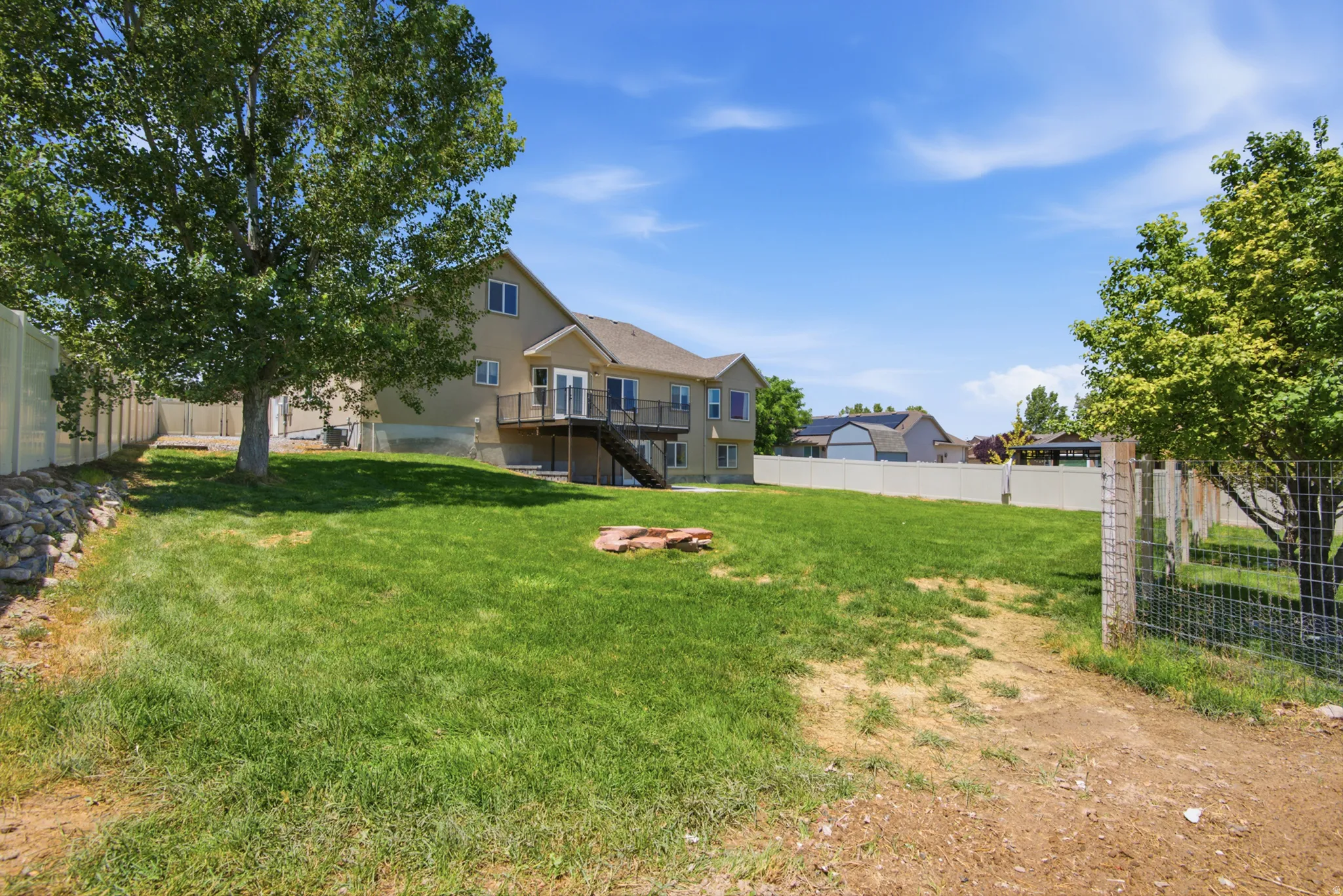 Expansive backyard with a manicured lawn, established trees, and perimeter fencing