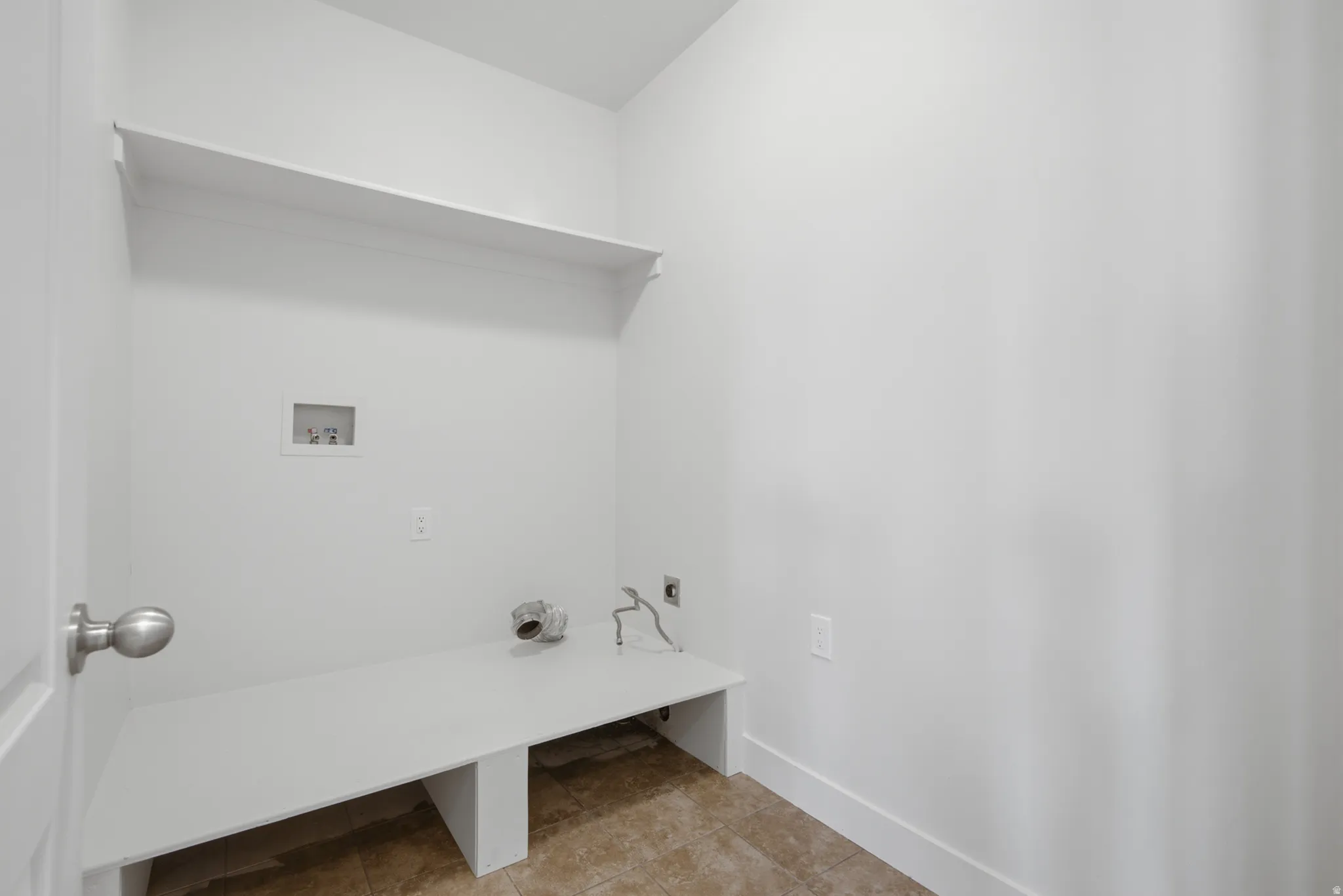 Dedicated laundry space featuring a built-in shelf, built-in counter, and tile flooring