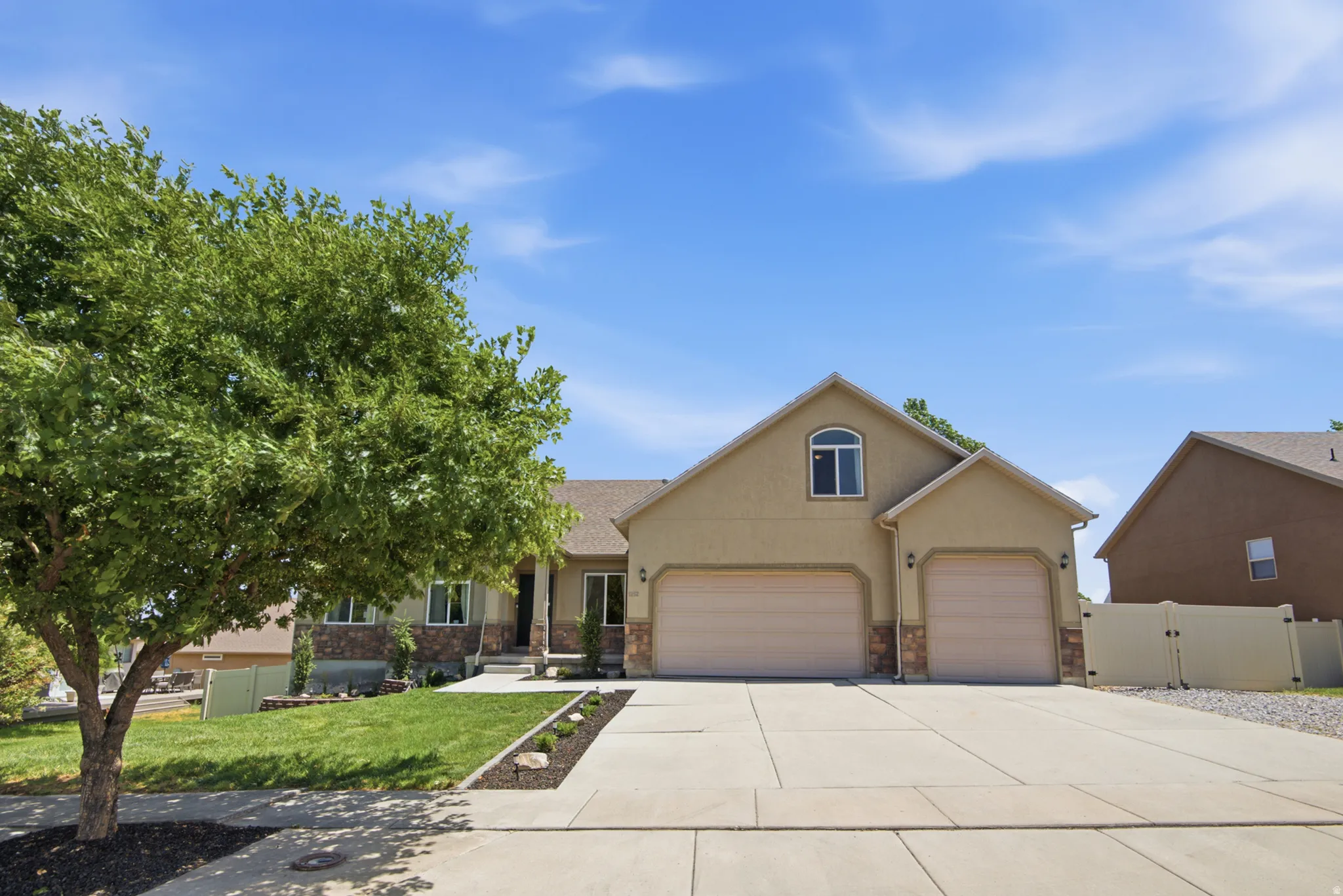 Exterior features include a two-car garage, a separate single-car garage, a concrete driveway, stone accents, and manicured landscaping