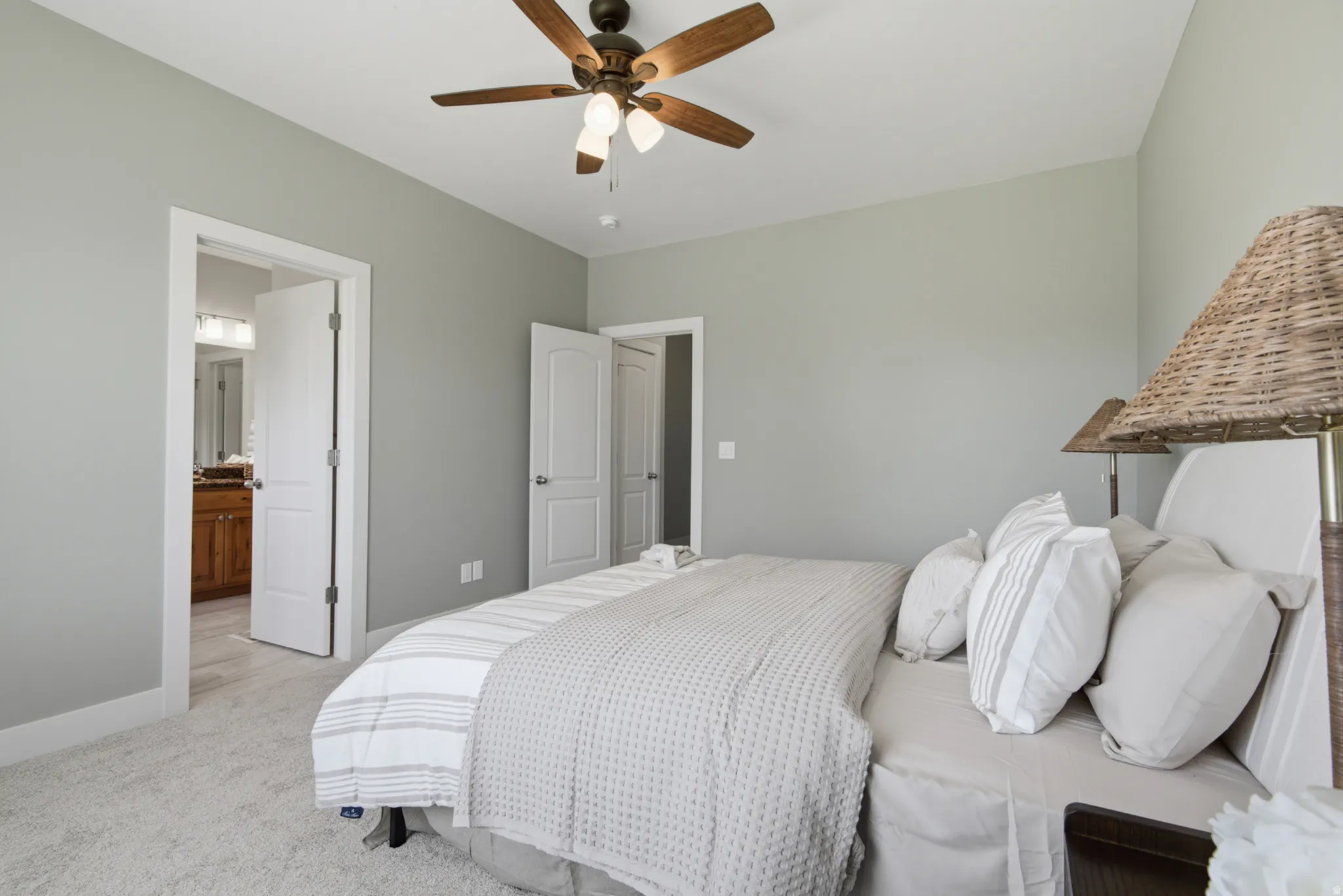 Neutral-toned room with a ceiling fan, light gray wall paint, white trim, and light-colored carpet flooring