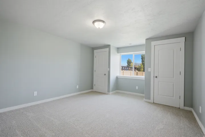 Spacious room featuring light gray carpeting and cool-toned wall paint