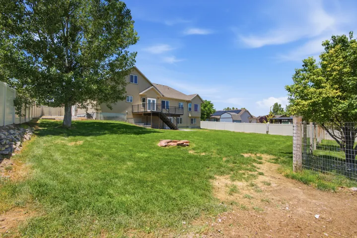 Expansive backyard with a manicured lawn, established trees, and perimeter fencing