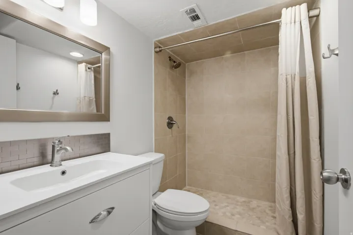 Bathroom featuring a vanity with an integrated sink, brushed metal hardware, and a subway tile backsplash