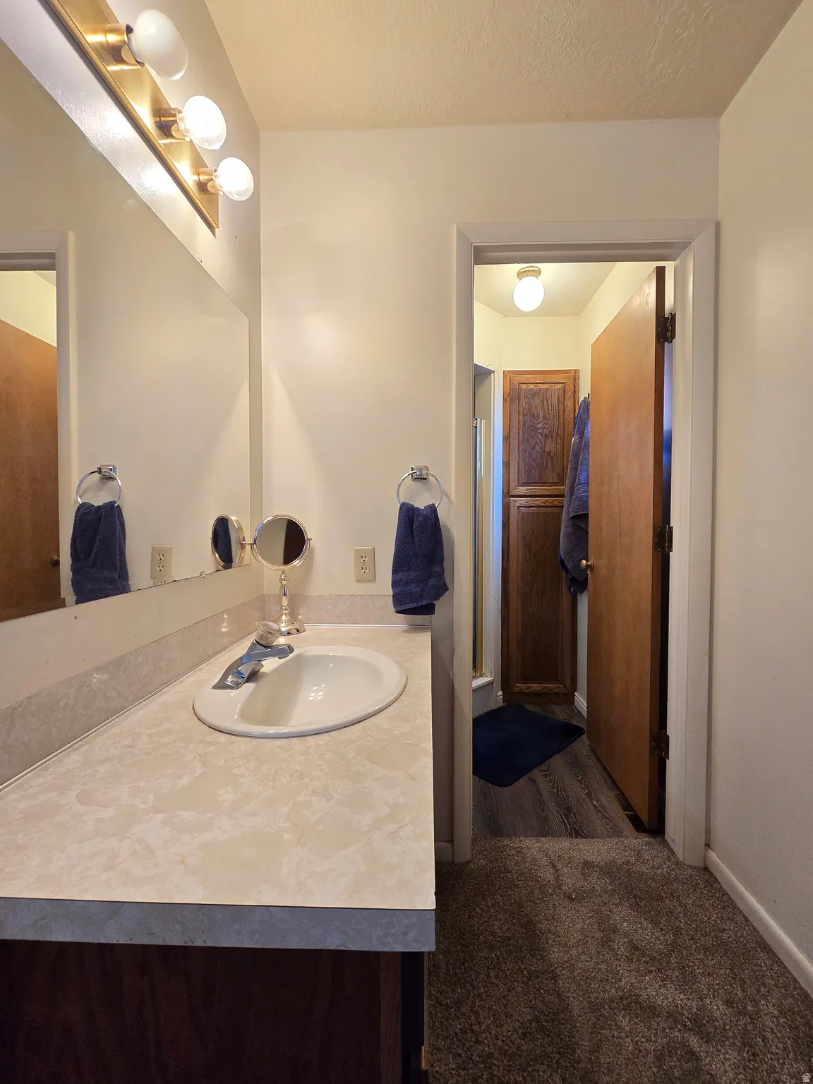 Bathroom vanity with a white oval sink, chrome faucet, and patterned countertop