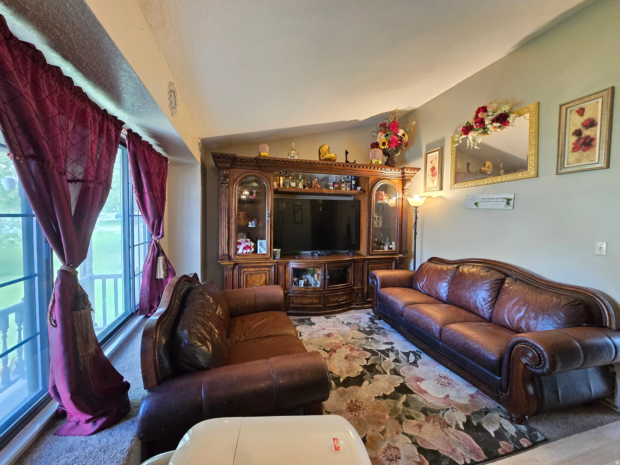 Spacious living area featuring a large window, neutral wall paint, and a built-in entertainment center with display cabinets