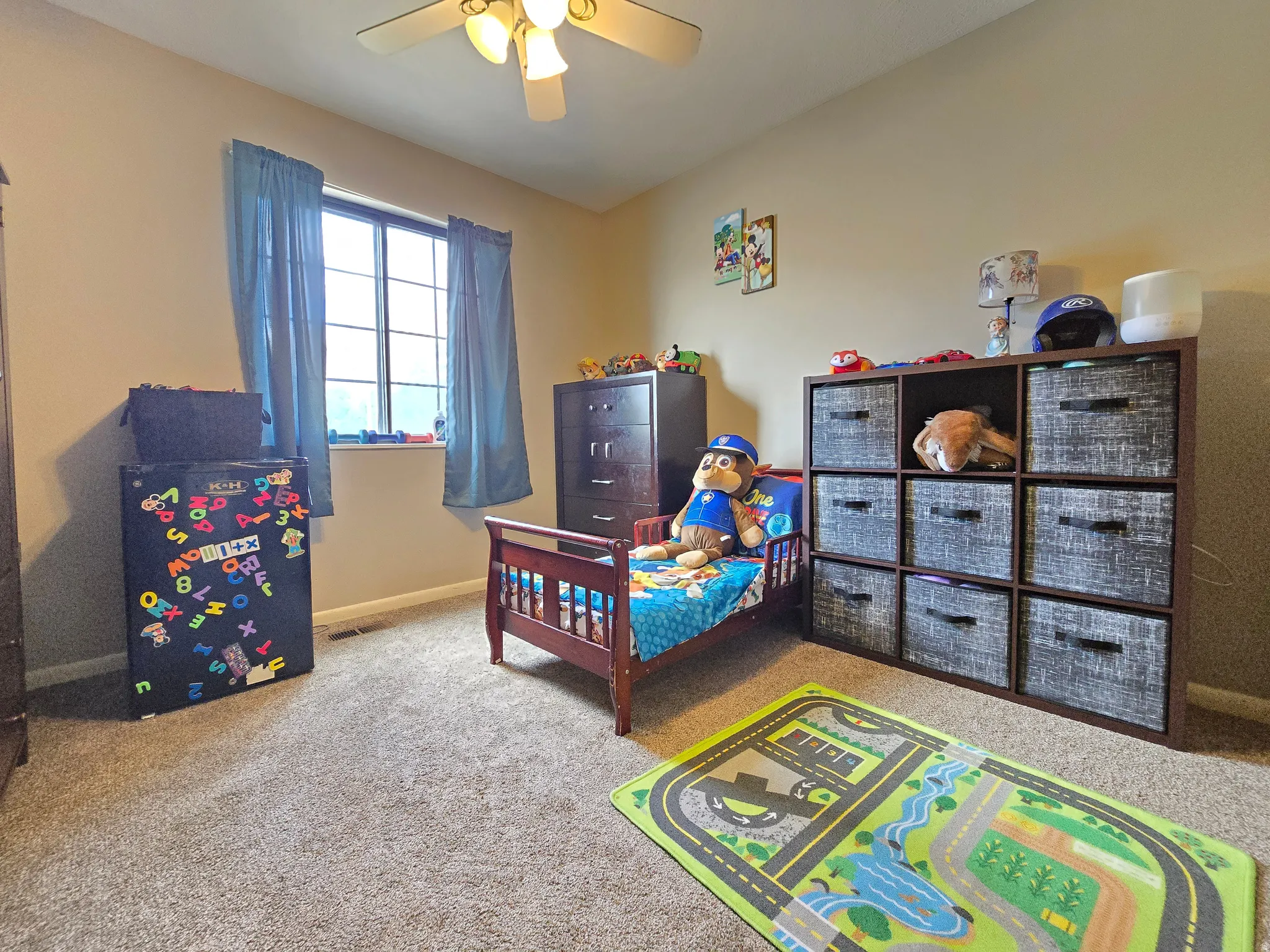 Carpeted room featuring a ceiling fan, a window with vertical mullions, and neutral wall tones