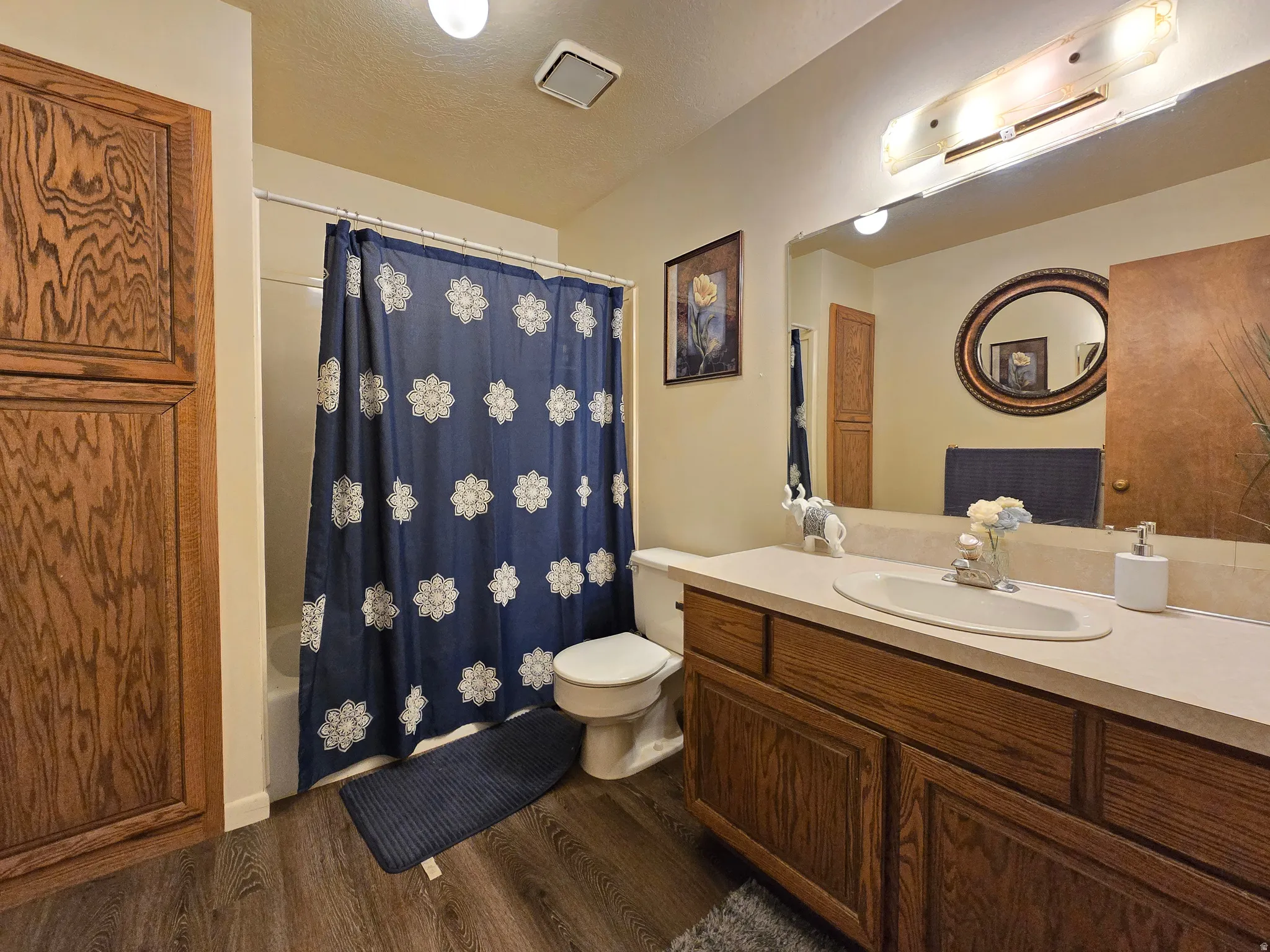 Bathroom featuring a single vanity with built-in cabinetry, an integrated sink, and a large wall-mounted mirror