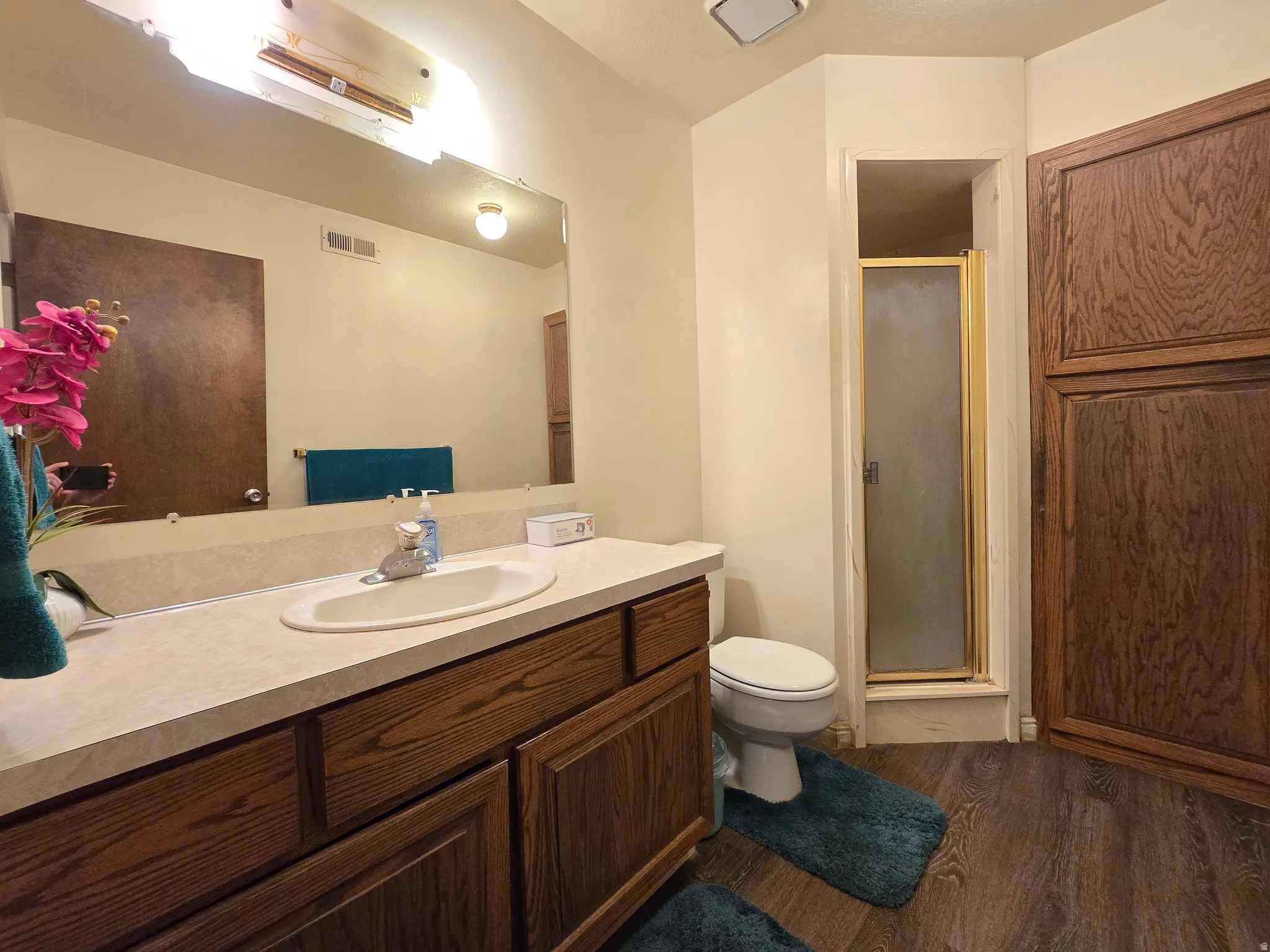 Bathroom featuring a single vanity with wood-finish cabinetry, a drop-in sink, and a light-colored countertop