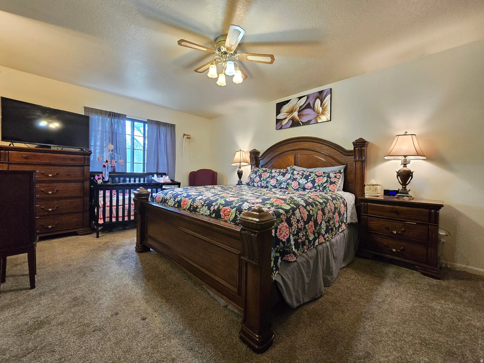 Carpeted room featuring a ceiling fan with integrated lighting, window with drapes, and neutral-toned walls