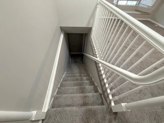 Carpeted staircase with white balusters and handrails