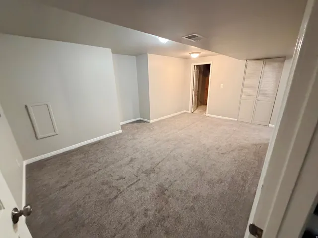 Carpeted room featuring light gray walls, white baseboards, and bi-fold louvered closet doors