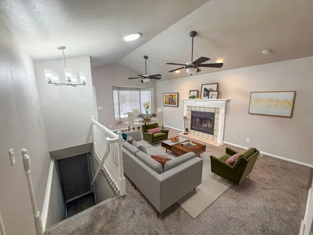 Living area with vaulted ceilings, a fireplace featuring a white mantel and tile surround, and recessed lighting