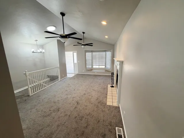 Spacious living area featuring vaulted ceilings, ceiling fans, recessed lighting, and grey carpet