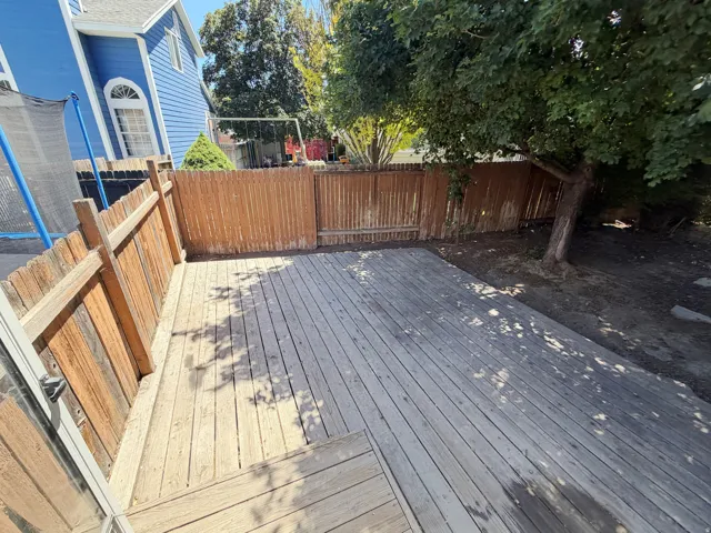 Spacious outdoor deck area featuring wood planking and privacy fencing