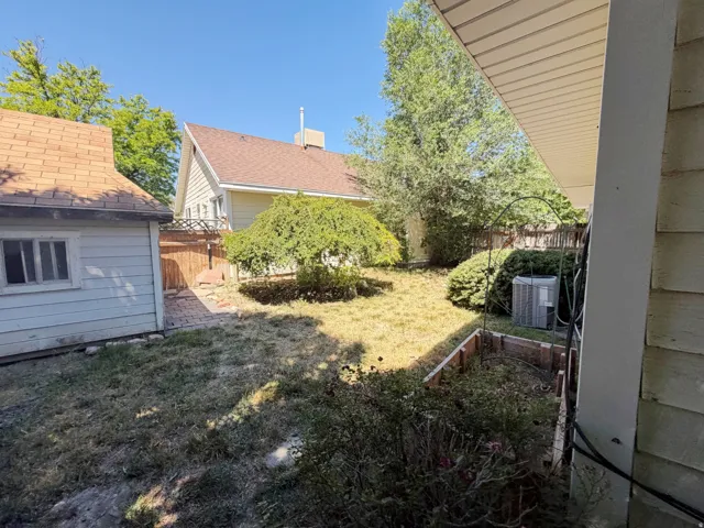 Expansive backyard featuring a mature deciduous tree, a brick paver pathway, and a detached structure with a shingle roof