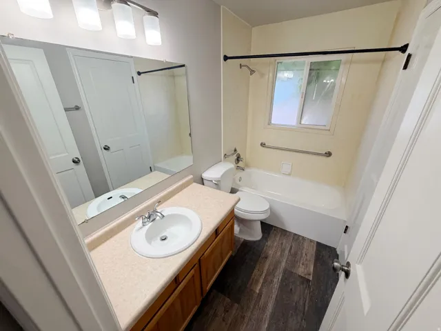 Bathroom featuring a single vanity with wood cabinetry, a laminate countertop, and an integrated sink