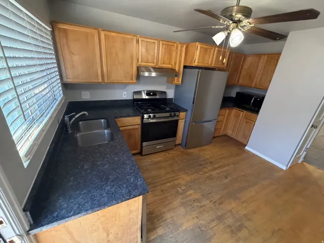 Kitchen featuring light wood cabinetry, dark speckled countertops, and stainless steel appliances