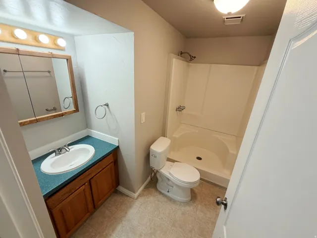 Bathroom featuring a vanity with wood-finish cabinetry, a white basin sink, and a blue countertop