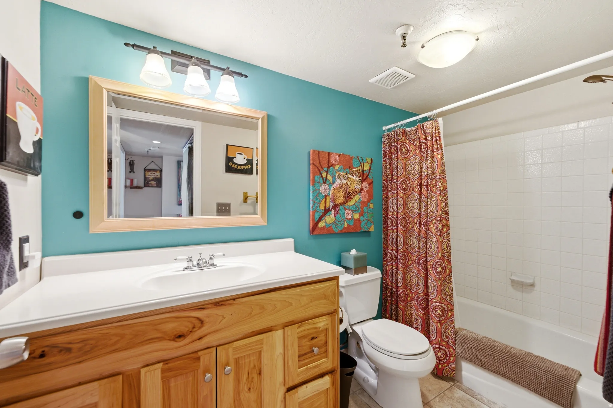 Bathroom vanity featuring a light wood-finish cabinet, white countertop with integrated sink, and an overhead vanity light fixture