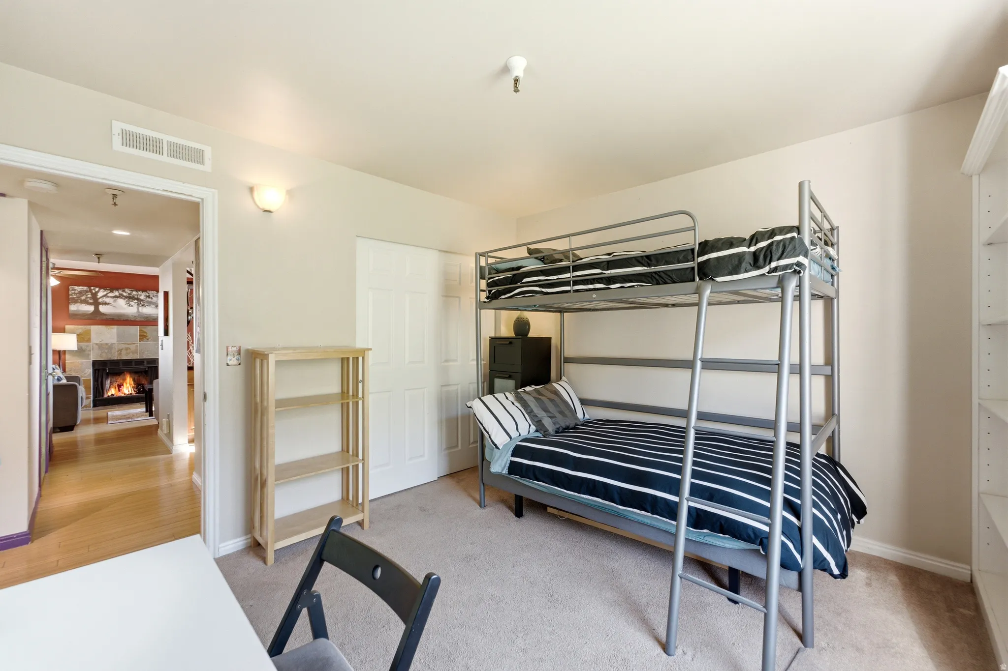Bedroom featuring neutral-toned carpeting, a built-in shelving unit, and a wall-mounted light fixture