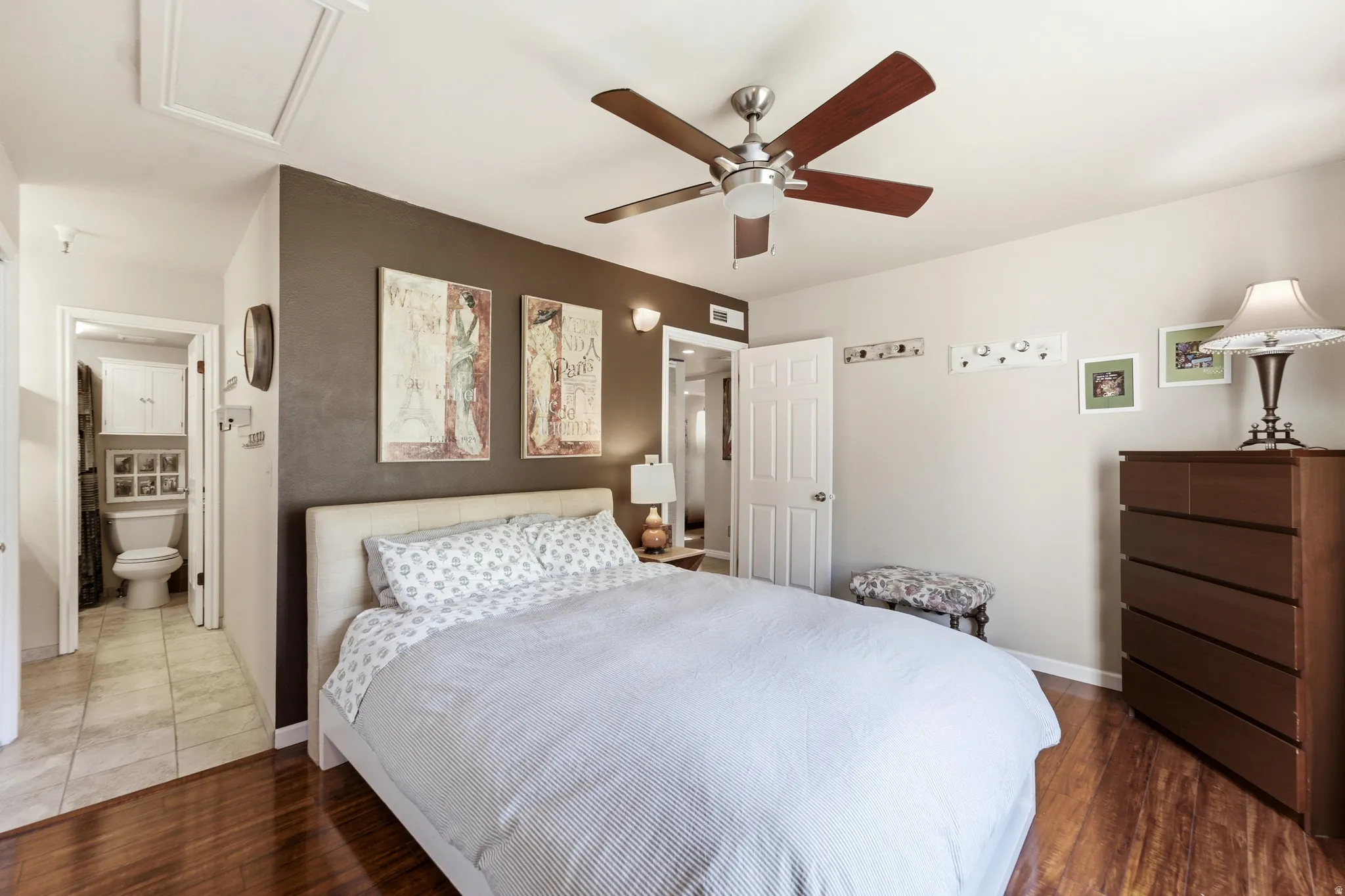 Bedroom featuring wood-finish flooring, a ceiling fan, and a light-toned door
