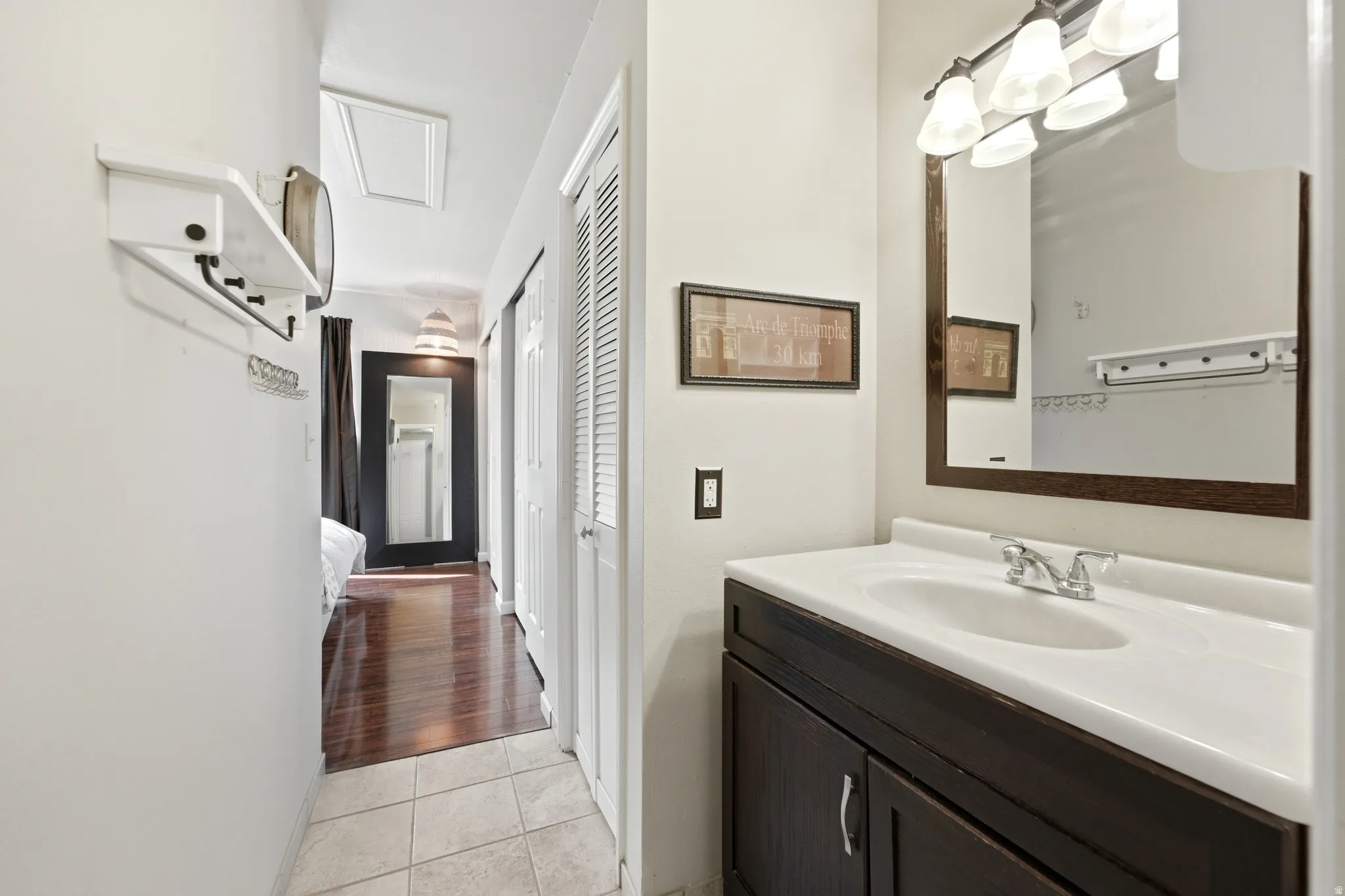 Bathroom vanity featuring a single basin sink, chrome faucet, and dark wood-finish cabinetry