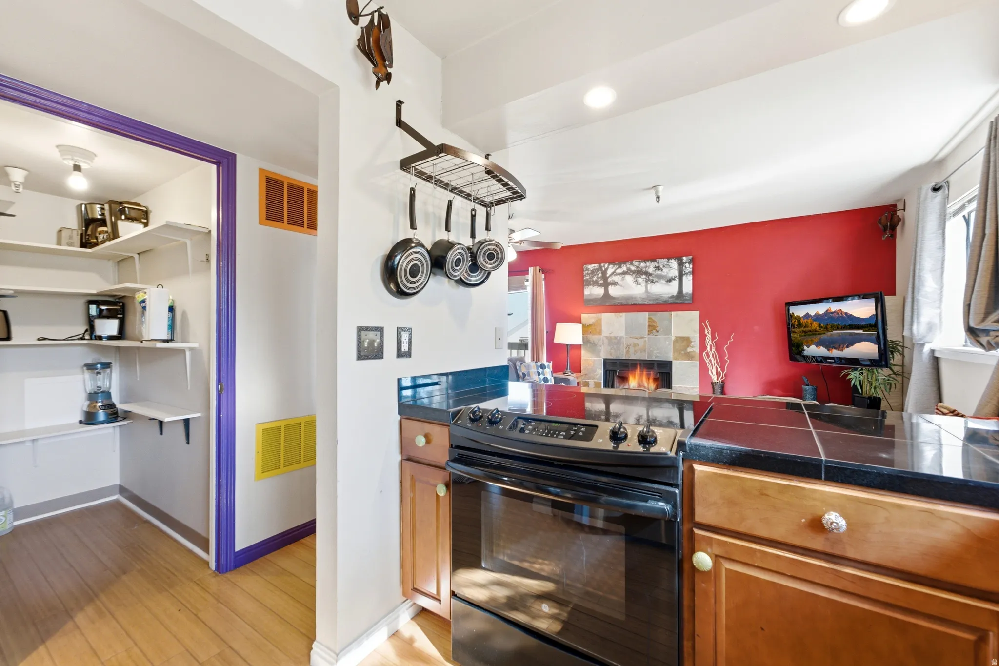 Kitchen with black range, dark countertop, and wood-finish cabinetry