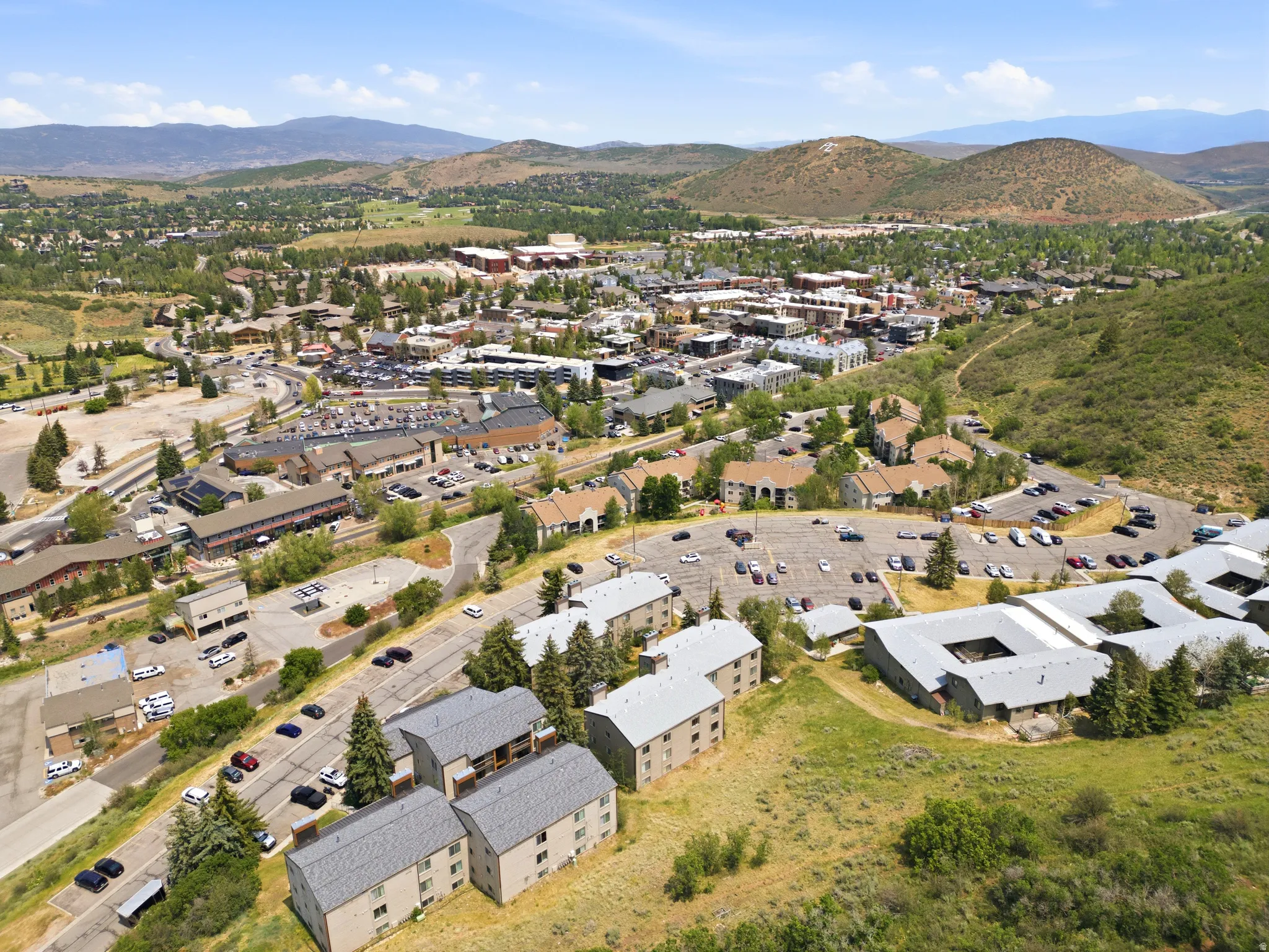 Aerial perspective showcasing a vibrant community with diverse architectural styles, surrounded by natural mountainous terrain