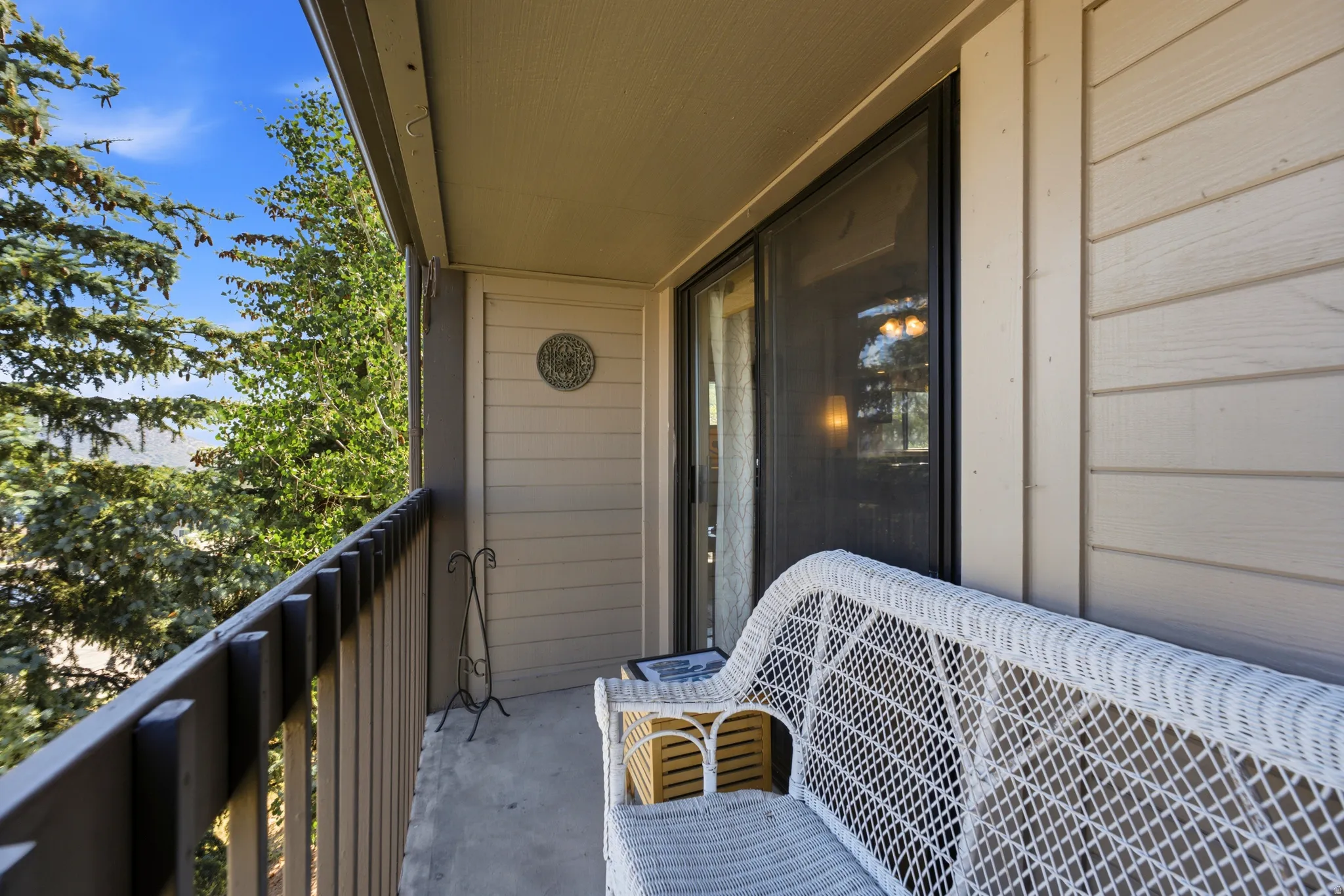 Private outdoor balcony featuring a sliding glass door entry, wood-finish siding, and a sturdy railing