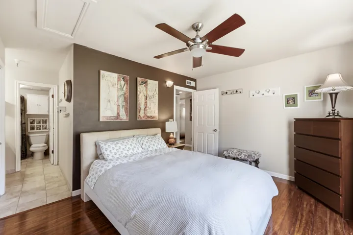 Bedroom featuring wood-finish flooring, a ceiling fan, and a light-toned door