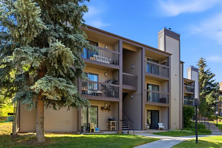 Multi-story exterior with private balconies, brown wood-paneled siding, and a concrete pathway