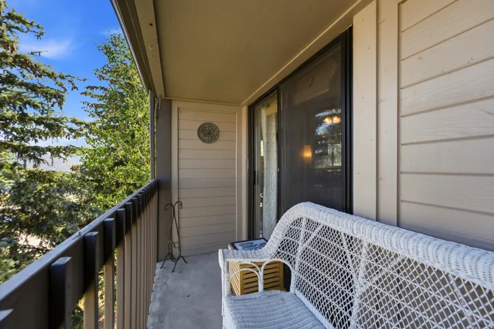 Private outdoor balcony featuring a sliding glass door entry, wood-finish siding, and a sturdy railing