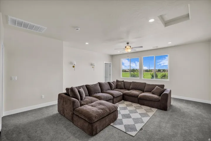 Spacious room featuring multiple windows, a ceiling fan, recessed lighting, and wall sconces